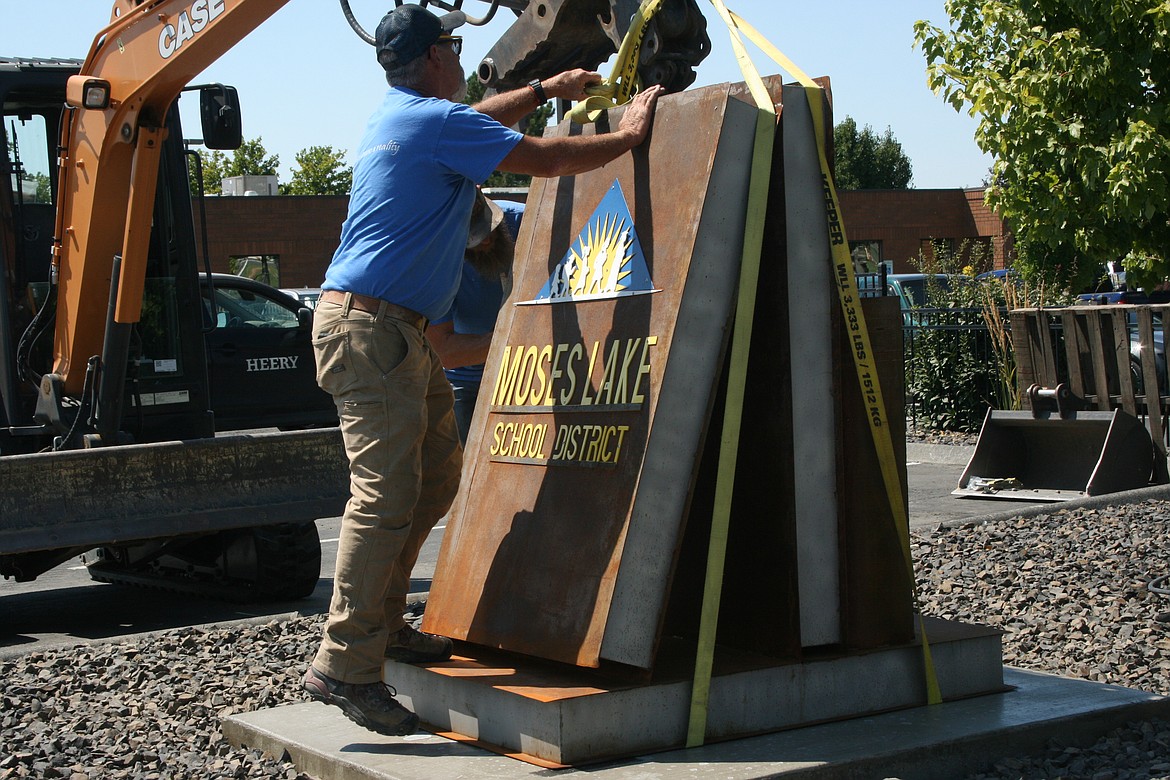 Steve Miers, Miers Construction, removes the straps from a sculpture outside the Moses Lake School District Learning Services Center during installation Monday. Multiple years of CB Tech students worked on the project.