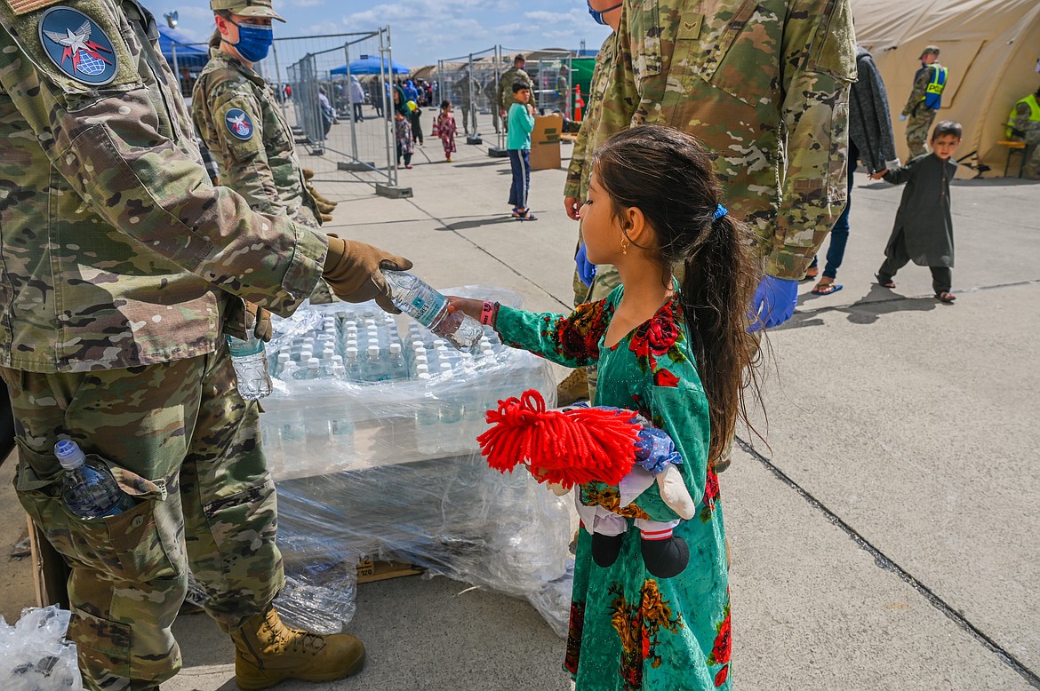 Airmen and Guardians from the 4th Space Operations Squadron, distribute water to a child at Ramstein Air Base, Germany, Aug. 25, 2021. Water and food distribution is one of the many ways that military members are contributing towards Operation Allies Refuge (U.S. Air Force photo by Senior Airman Jan K. Valle).