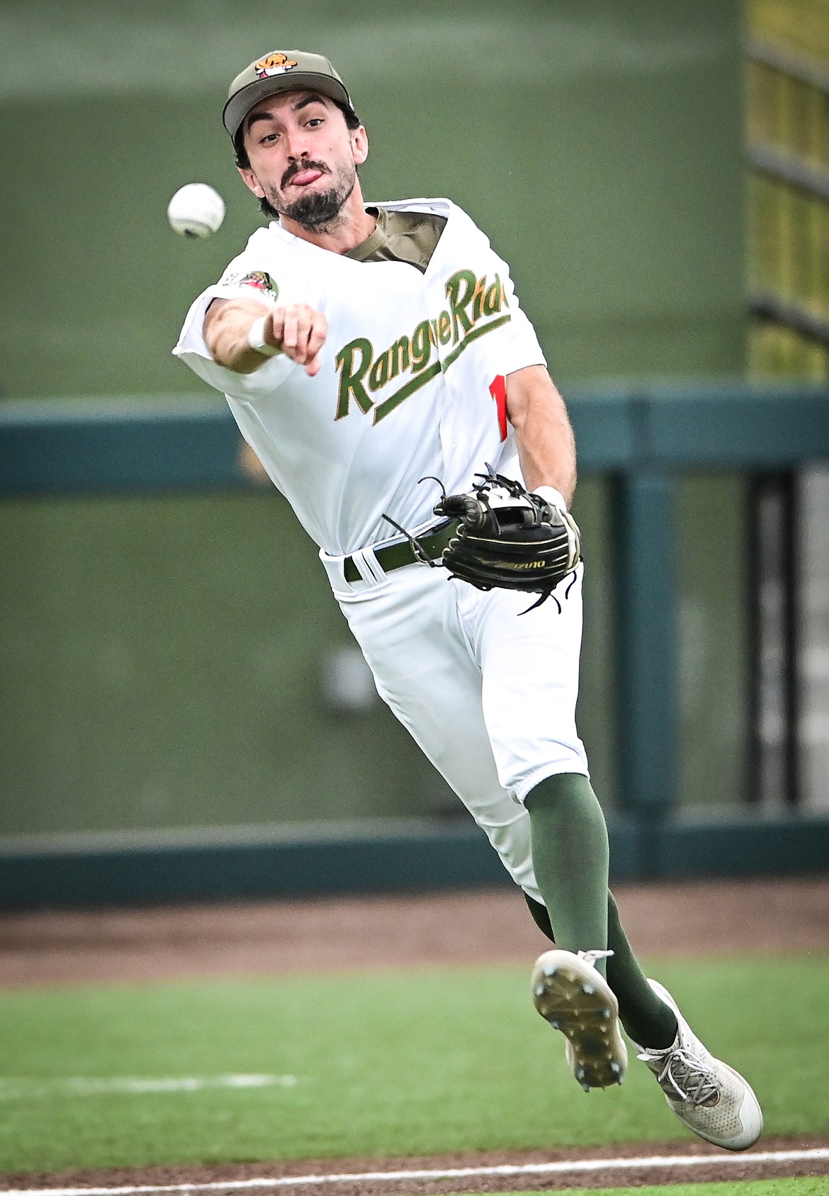 Glacier third baseman Brandt Broussard (1) charges and fires to first after fielding a slow-roller hit by Great Falls' Collin Runge at Flathead Field on Thursday, Aug. 11. Runge beat out the throw for a single. (Casey Kreider/Daily Inter Lake)