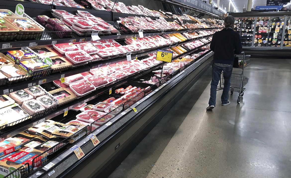 In this May 10, 2020 file photo, a shopper pushes his cart past a display of packaged meat in a grocery store in southeast Denver. Prices at the wholesale level fell from June to July, the first month-to-month drop in more than two years and a sign that some of the U.S. economy's inflationary pressures cooled last month. Thursday’s report from the Labor Department showed that the producer price index — which measures inflation before it reaches consumers — declined 0.5% in July. (AP Photo/David Zalubowski, File)