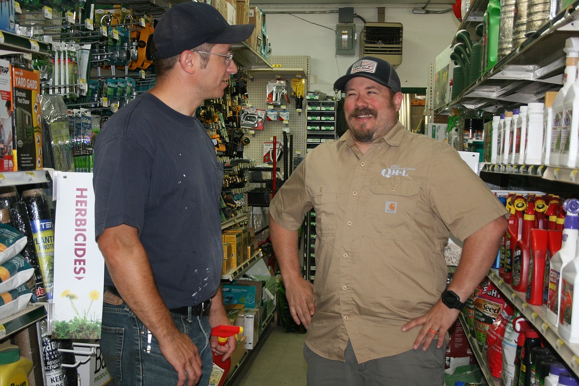 Quincy Hardware and Lumber manager Jeremy Sewall (right) helps customer Stephen Harder find the right lawn products.