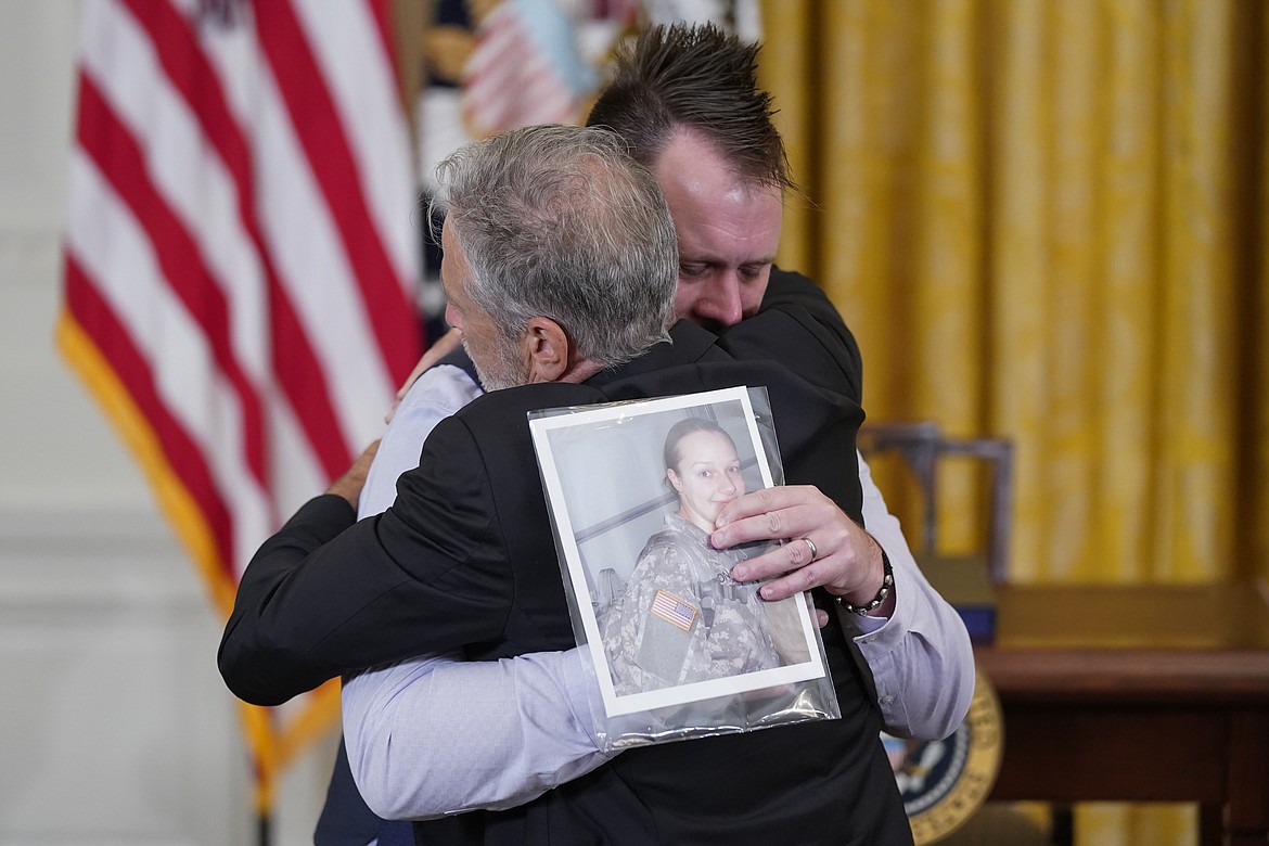 Jon Stewart hugs Sri Benson, husband of Katie Benson who served in Kuwait and died of mesothelioma, as they arrive to attend an event where President Joe Biden will sign the "PACT Act of 2022" in the East Room of the White House, Wednesday, Aug. 10, 2022, in Washington. (AP Photo/Evan Vucci)