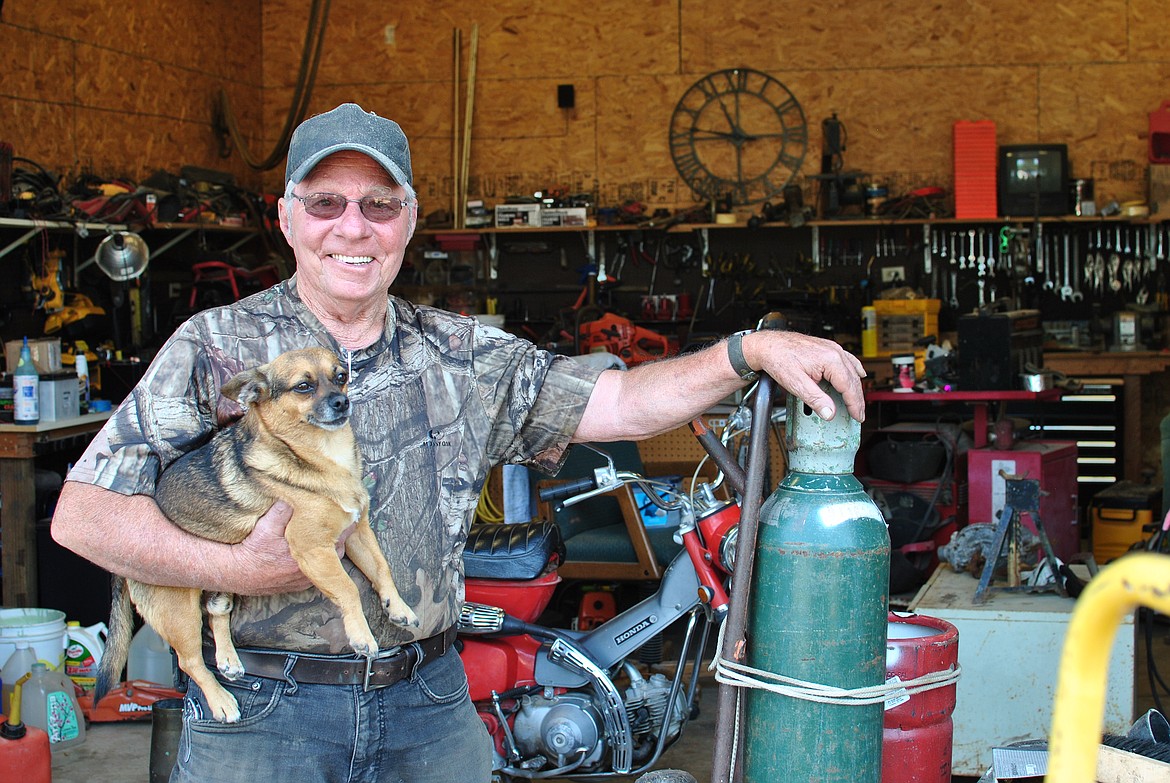 On a warm August morning David Hannah stands out front of his garage work shop in St. Regis with his dog Bubba. Hannah opened a small engine repair business this past year and has had a full work load all spring and summer. (Mineral Independent/Amy Quinlivan)