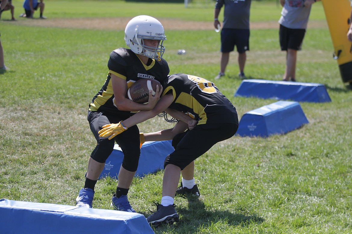 MARK NELKE/Press
Eli Zember carries and ball as Landon Capaul applies the tackle during a Junior Tackle football camp Friday at Lake City High. Both are entering the seventh grade.
