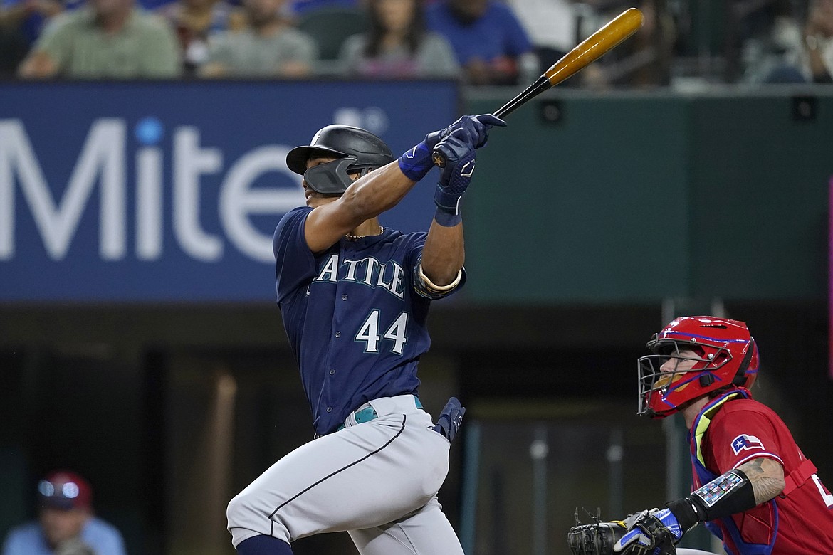 Seattle Mariners' Julio Rodriguez (44) follows through on a two-run single next to Texas Rangers catcher Jonah Heim during the fourth inning of a baseball game in Arlington, Texas, Friday, Aug. 12, 2022.