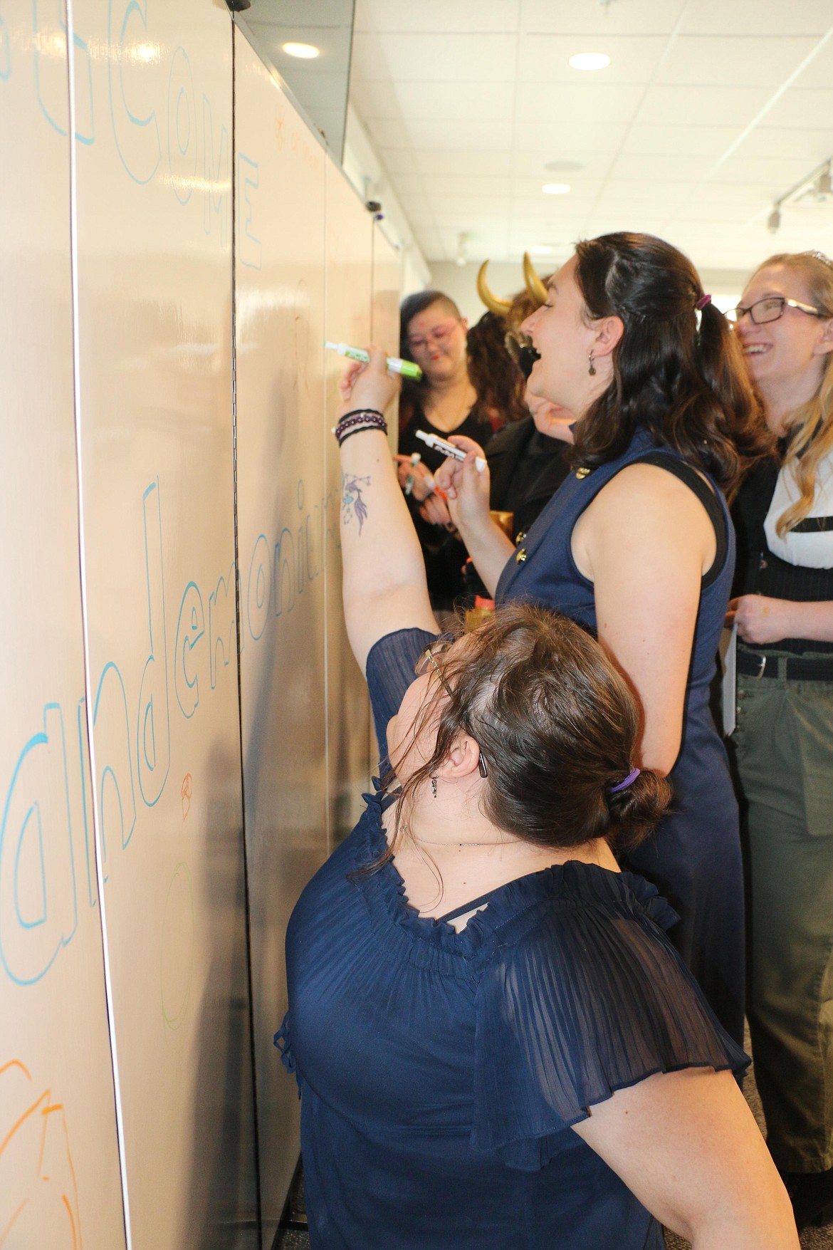 Sandemonium Lite attendees laugh as they add messages to a white board set up at the mid-May event for notes, drawings and more.