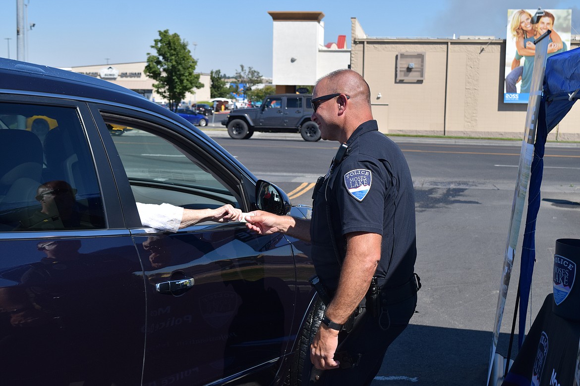 Moses Lake Police Department Capt. Mike Williams takes a donation on Monday from a customer at Sun Splash Car Wash, where MLPD staged a fundraiser for the privately funded Blue Bridge Program, which gives patrol officers a prepaid debit card that allows them to help people in need with everything from a meal to a tank of gas.