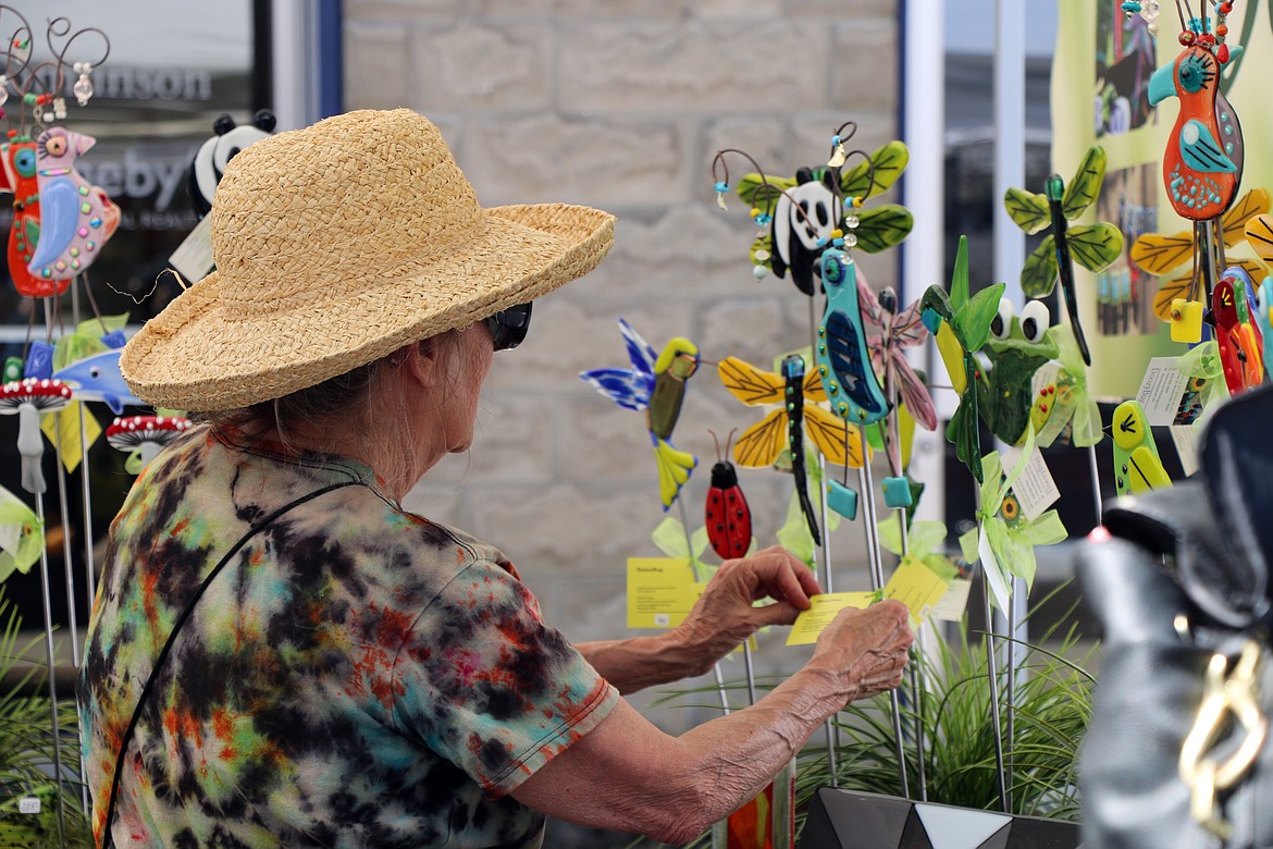 A shopper browses the booth of DoozyBug art glass studio of Richland, Wash., during the Pend Oreille Arts Council's annual Arts & Crafts Fair on Saturday.
