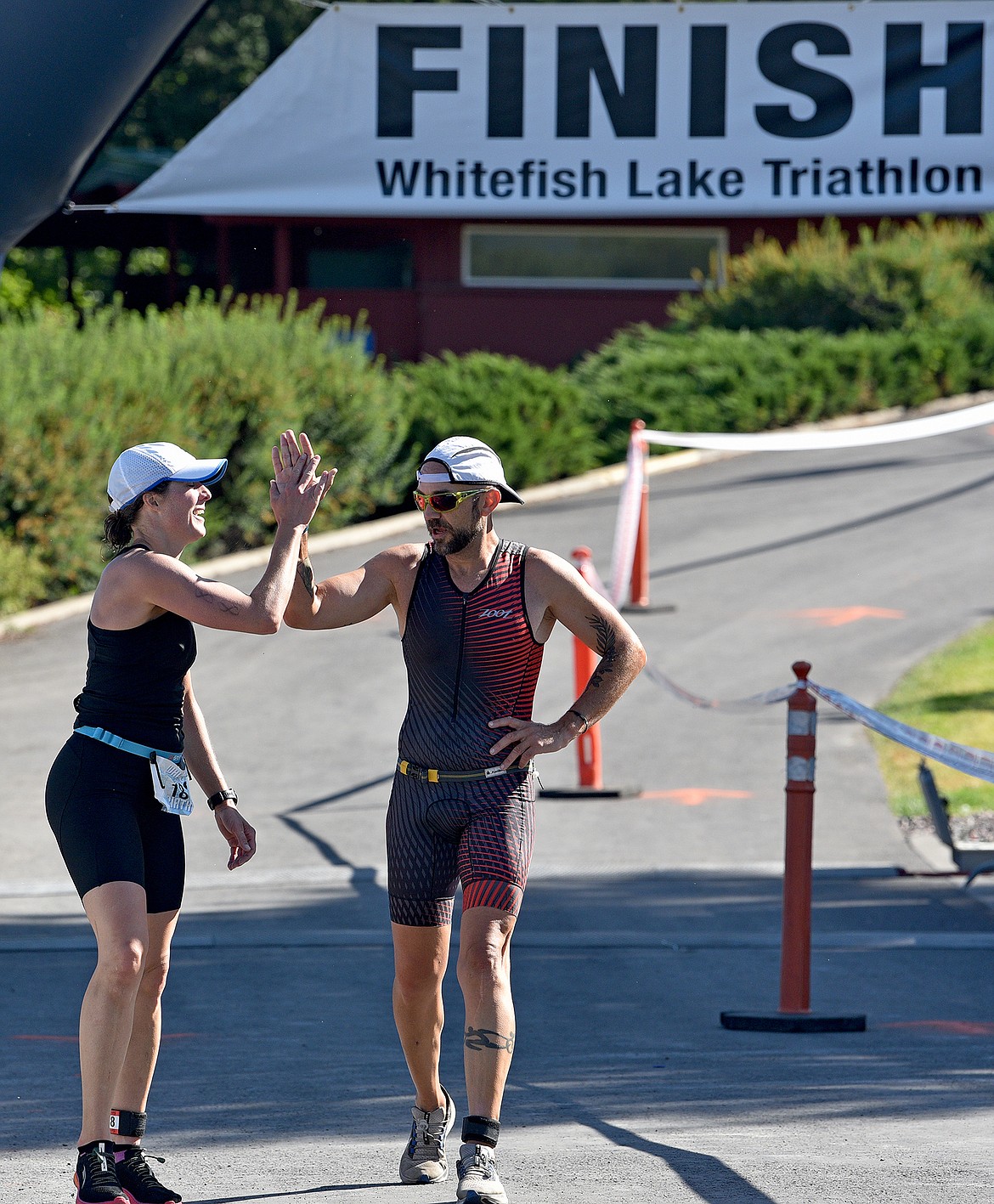 Competitors high-five each other after crossing the finish line of the Whitefish Lake Triathlon on Sunday, Aug. 14 at City Beach. (Whitney England/Whitefish Pilot)