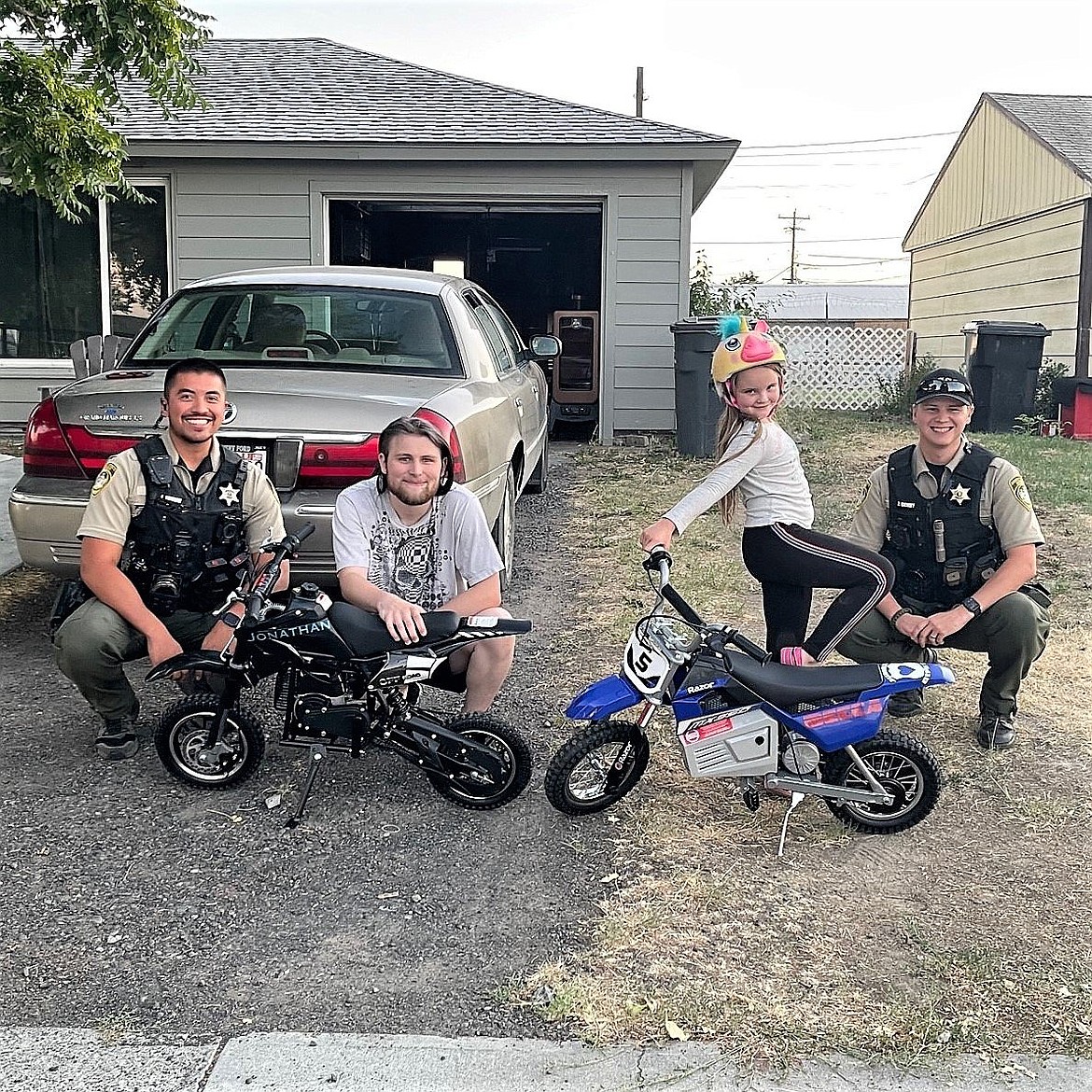 Deputy Luis Jimenez, left, and Deputy Zane Bundy, right, pose with a couple members of a Larson Community family whose electric bikes were stolen.