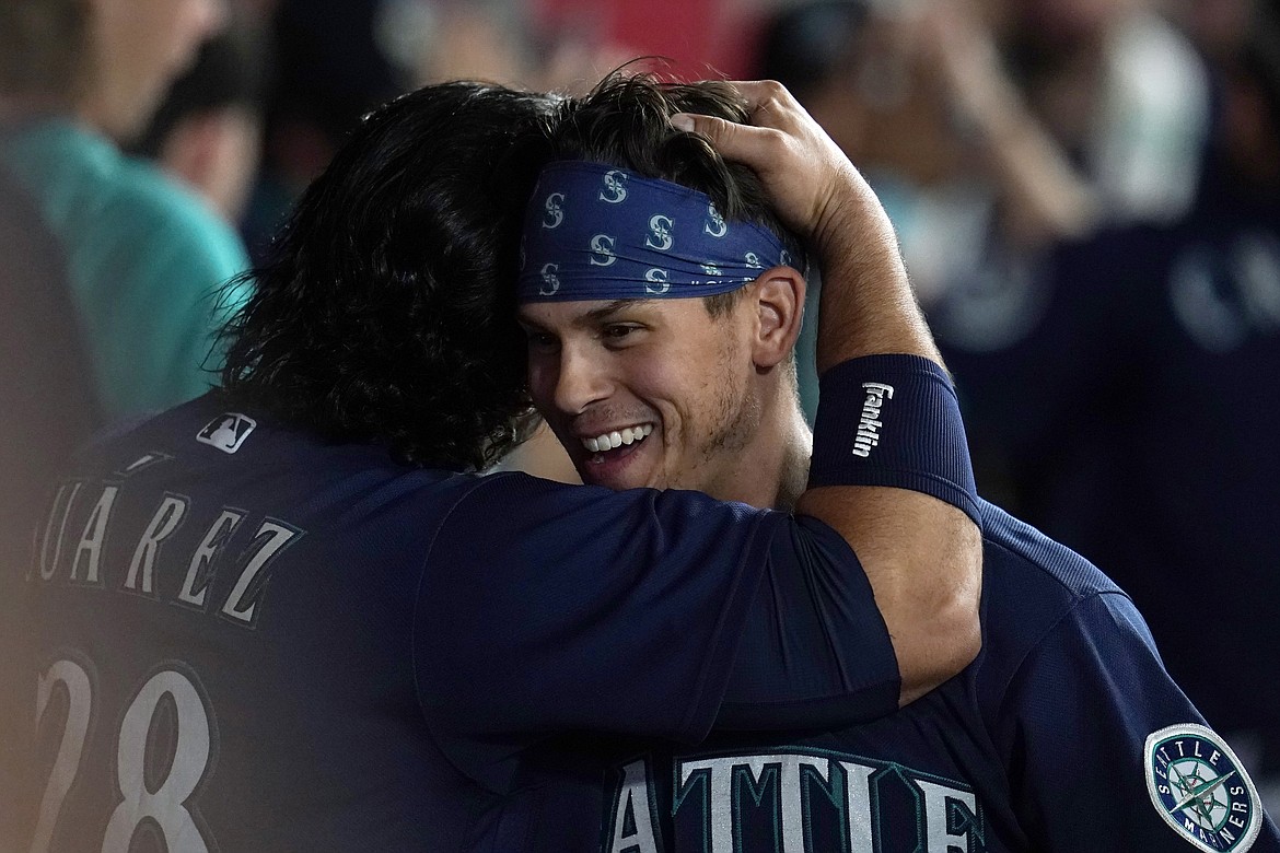 Seattle Mariners' Sam Haggerty, right, is hugged by Eugenio Suarez after Haggerty scored on a single by Ty France during the sixth inning of the team's baseball game against the Los Angeles Angels on Tuesday, Aug. 16, 2022, in Anaheim, Calif.