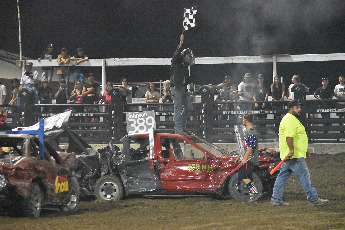 CJ Johnson who won the ’80s Demo, stands atop his car holding the final race flag celebrating his win.