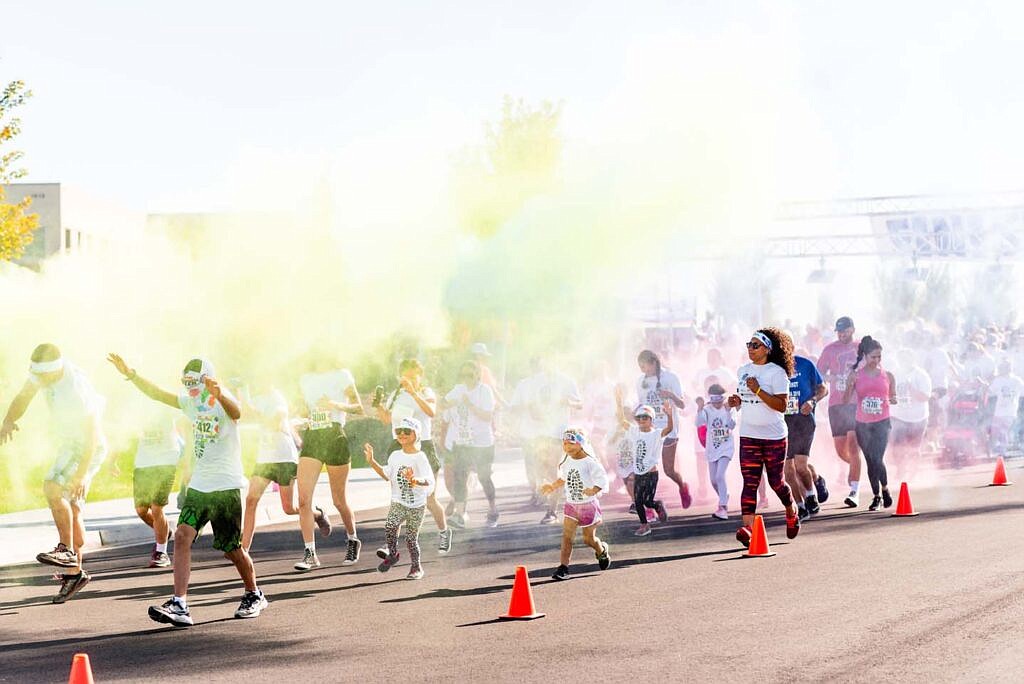 Runners trek through colored powder wearing white shirts to catch the powder as they run. The bright result is part of the fun of participating in a color run.