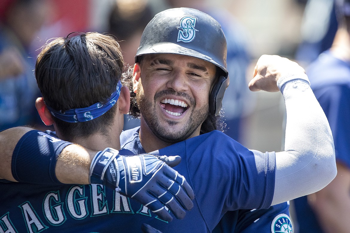 Seattle Mariners' Eugenio Suarez, right, hugs Sam Haggerty in the dugout to celebrate Suarez's two-run home run against the Los Angeles Angels during the fifth inning of a baseball game in Anaheim, Calif., Wednesday, Aug. 17, 2022.