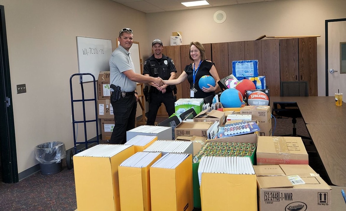 Soap Lake Police Chief Ryan Cox, left, shakes hands with Soap Lake School District Superintendent Kim Casey while Officer Robert Geates looks on. Cox and Gates delivered about $1,600 worth of school supplies to the district Thursday.