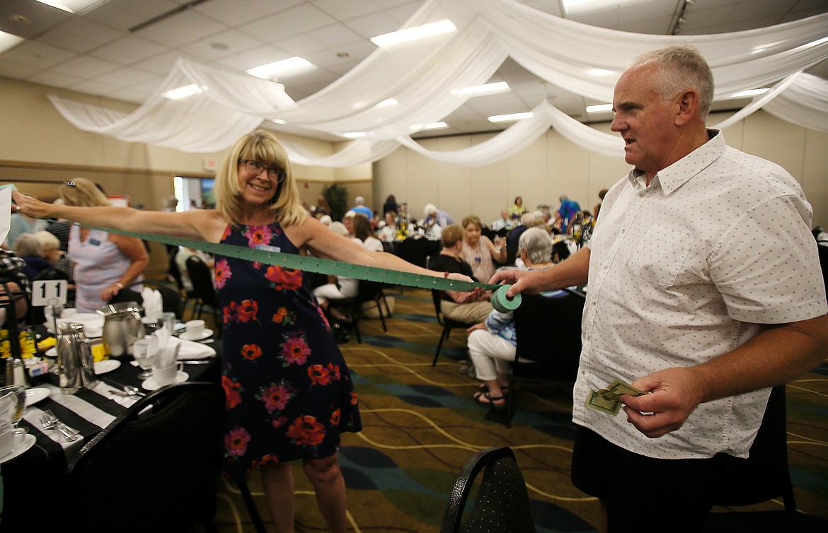 Outgoing 3Cs President Rhonda Newton unrolls a wingspan of raffle tickets Friday with assistance from longtime boyfriend Art Dietz during the 3Cs Appreciation Lunch in the Best Western Plus Coeur d'Alene Inn.