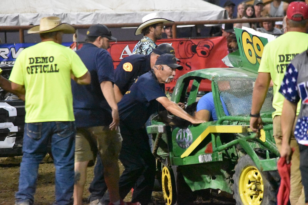 Aj Hara rests in his car as demo officials and EMS personnel check to see if he is okay after rolling his car at the demo derby.