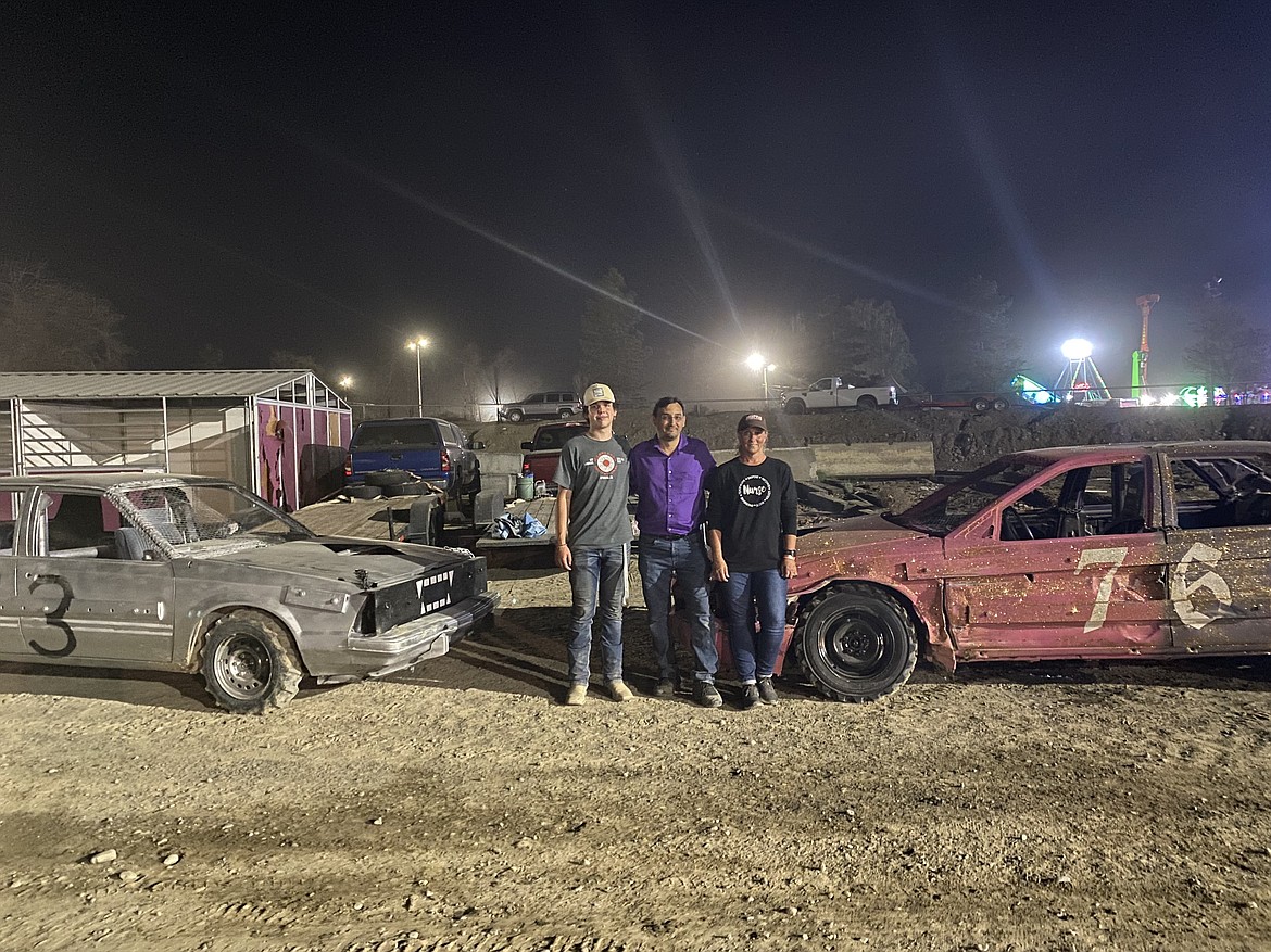 From left to right, Cameron Zabala, Tony Welsh and Cindy Welsh pose in front of Zabala and Cindy’s cars at the 2022 Northwest Ag Demolition Derby in Moses Lake.