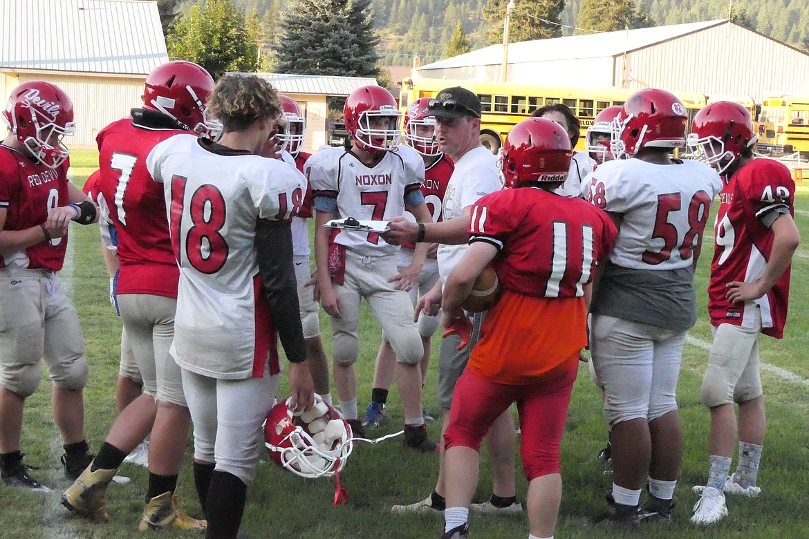 Noxon football coach Lucas MacArthur talks to players in a huddle during the school's recent scrimmage.  The Red Devils open the 2022 season at home this Saturday against Heart Butte.  (Chuck Bandel/VP-MI)