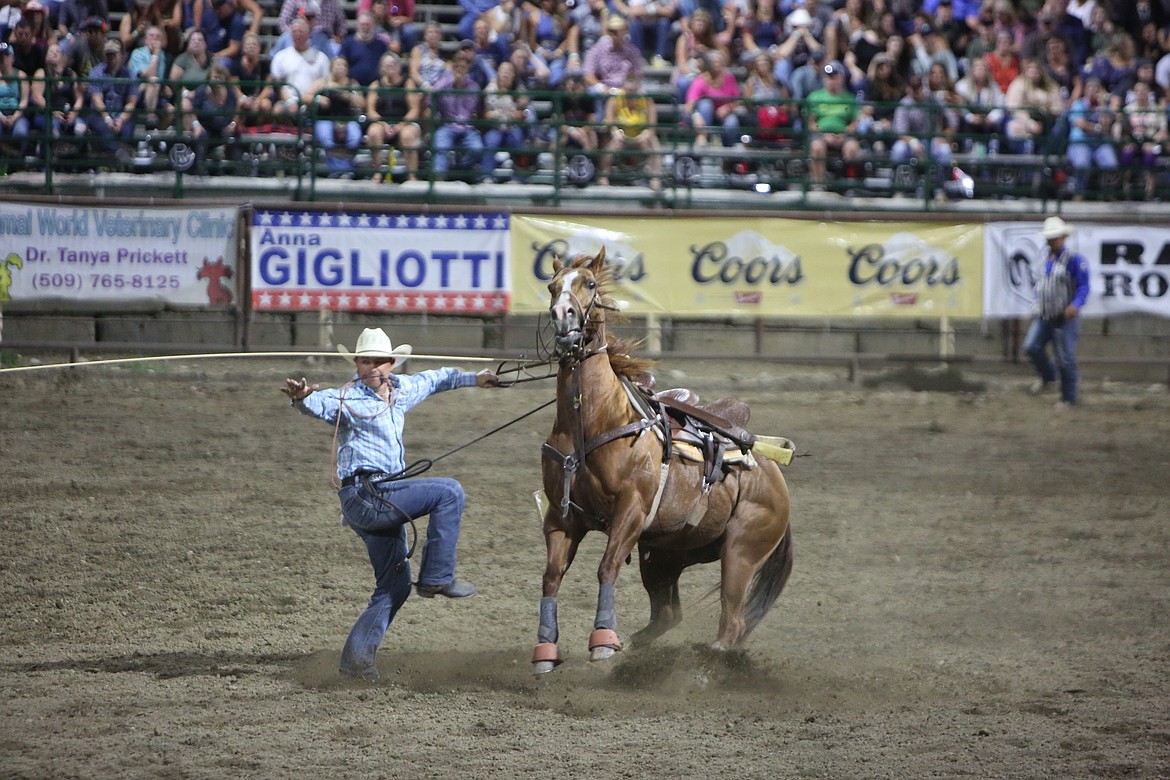 A rider leaps off a horse during the tie-down roping event, where a steer is roped before having its legs tied by a rider.