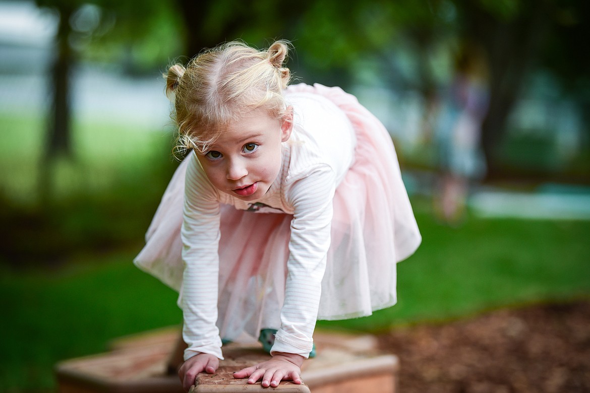 Natalia crawls across a balance beam outside the preschool at The Birds Nest Early Learning Village in Kalispell on Friday, Aug. 26. (Casey Kreider/Daily Inter Lake)