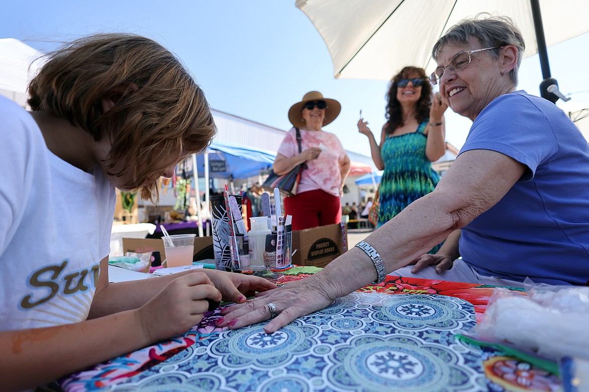 Olivia Paris paints the nails of Nancy Lemke at the new Columbia Falls Farmers Market July 31. (Jeremy Weber/Daily Inter Lake)