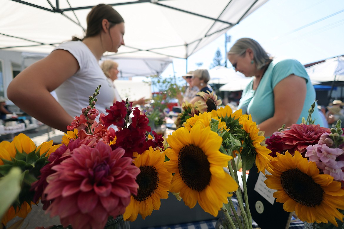 Canyon Masters talks with customers behind bouquets of fresh flowers by Ruby Connor at the new Columbia Falls Farmers Market July 31. (Jeremy Weber/Daily Inter Lake)