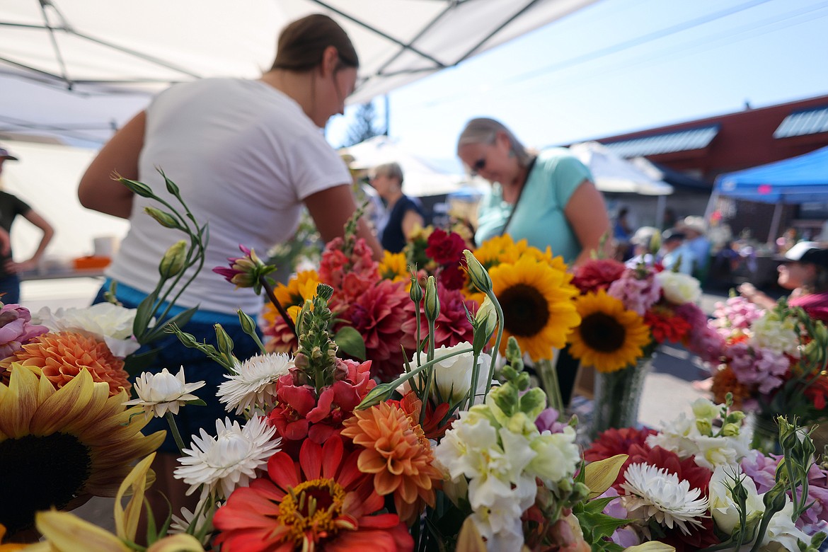 Canyon Masters talks with customers behind bouquets of fresh flowers by Ruby Connor at the new Columbia Falls Farmers Market July 31. (Jeremy Weber/Daily Inter Lake)