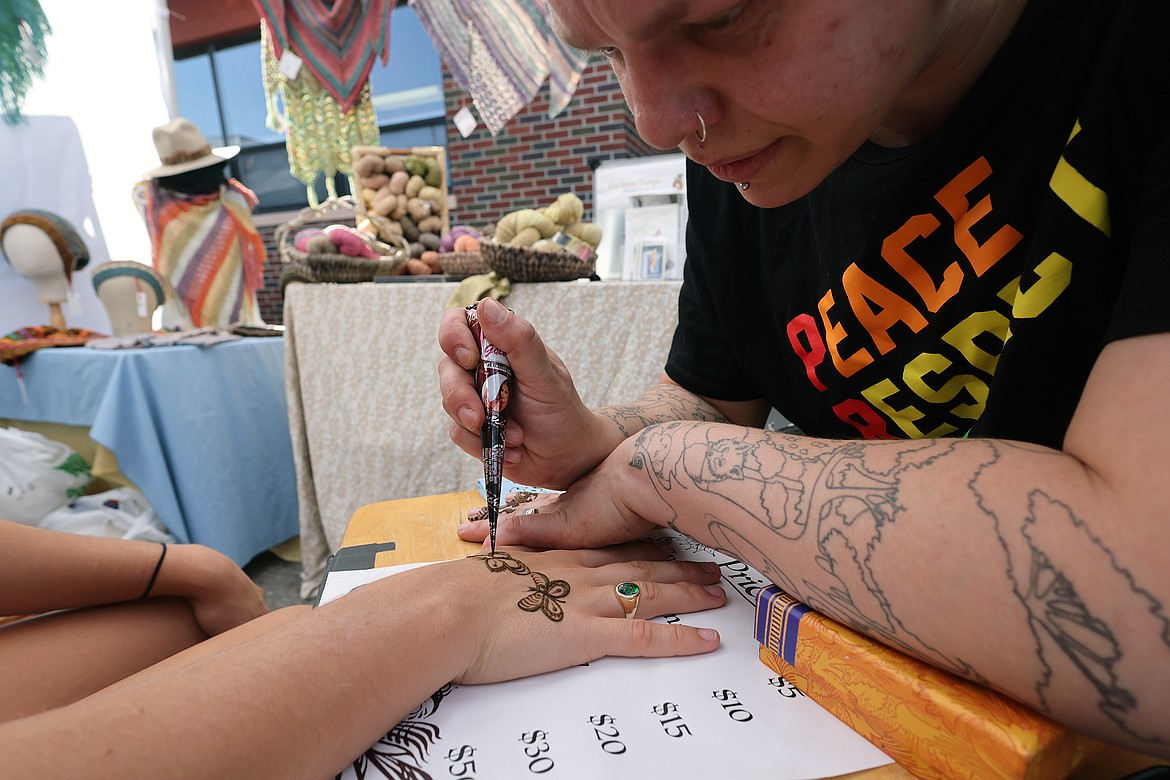 Julian Keller-King works on a butterfly henna tattoo at the new Columbia Falls Farmers Market July 31. (Jeremy Weber/Daily Inter Lake)