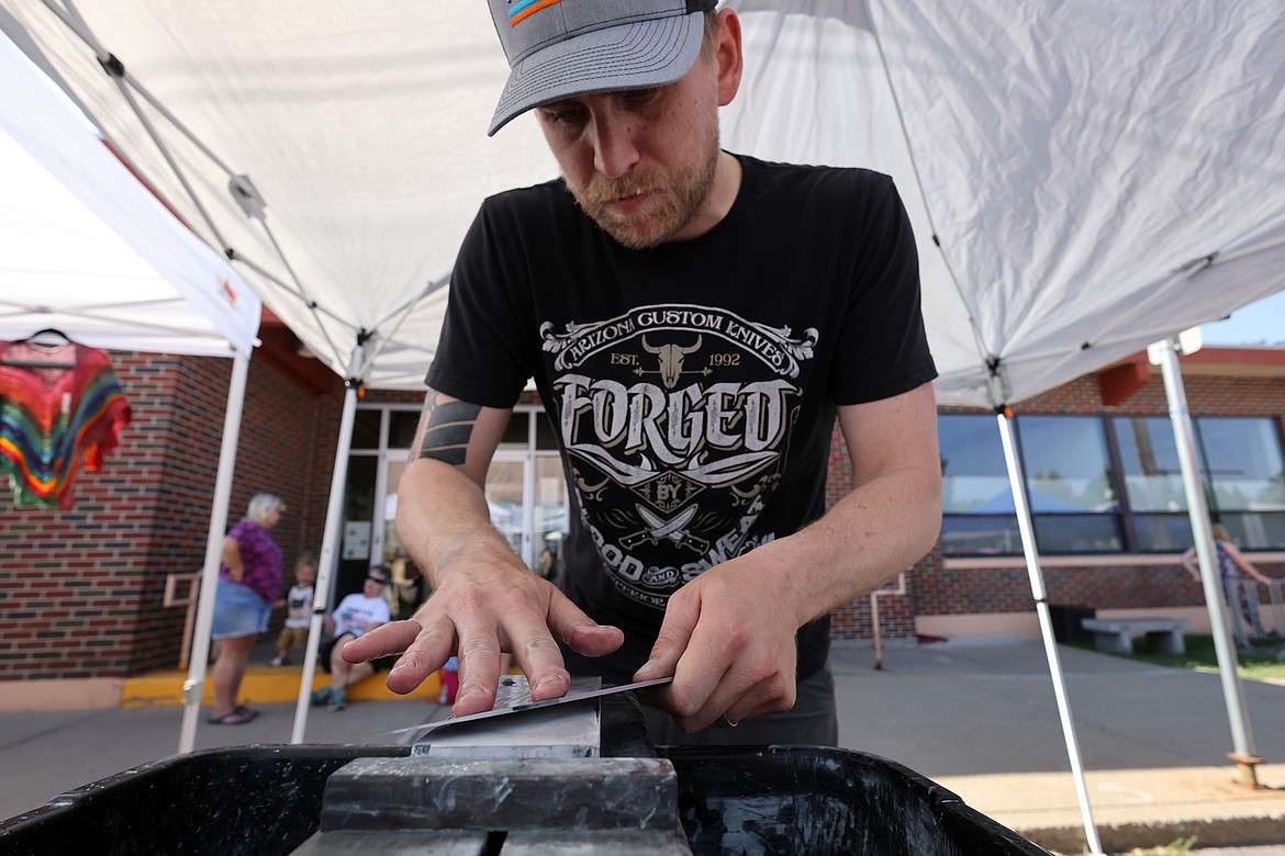 Jesse Jarosz of Jarosz Knives sharpens a customer's blade at the new Columbia Falls Farmers Market July 31. (Jeremy Weber/Daily Inter Lake)