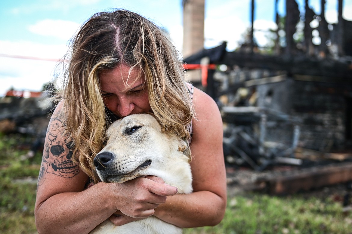 Desiree Brewer embraces one of the family's two dogs, Montana, a 1-year-old yellow Lab mix who alerted the family to an early-morning fire that destroyed their house along Tronstad Road. The family credits the dog with saving their lives. (Casey Kreider/Daily Inter Lake)