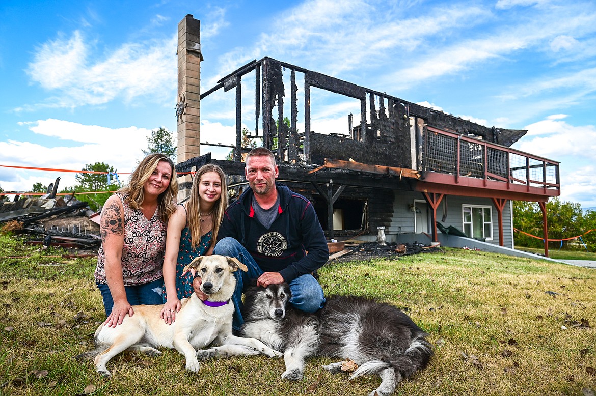 From left, Desiree Brewer, Brooke Brewer and Daniel Works with their dogs Montana, a yellow Lab/husky mix and Bandit, an Alaskan malamute mix, outside their home they lost in a fire along Tronstad Road on Saturday, Aug. 27. Montana alerted the family to the early-morning blaze. They believe the dog saved their lives. (Casey Kreider/Daily Inter Lake)