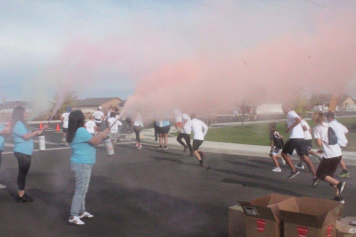 Volunteers douse runners in powdered paint at the Columbia Basin Health Association’s Color Run starting line on Saturday.