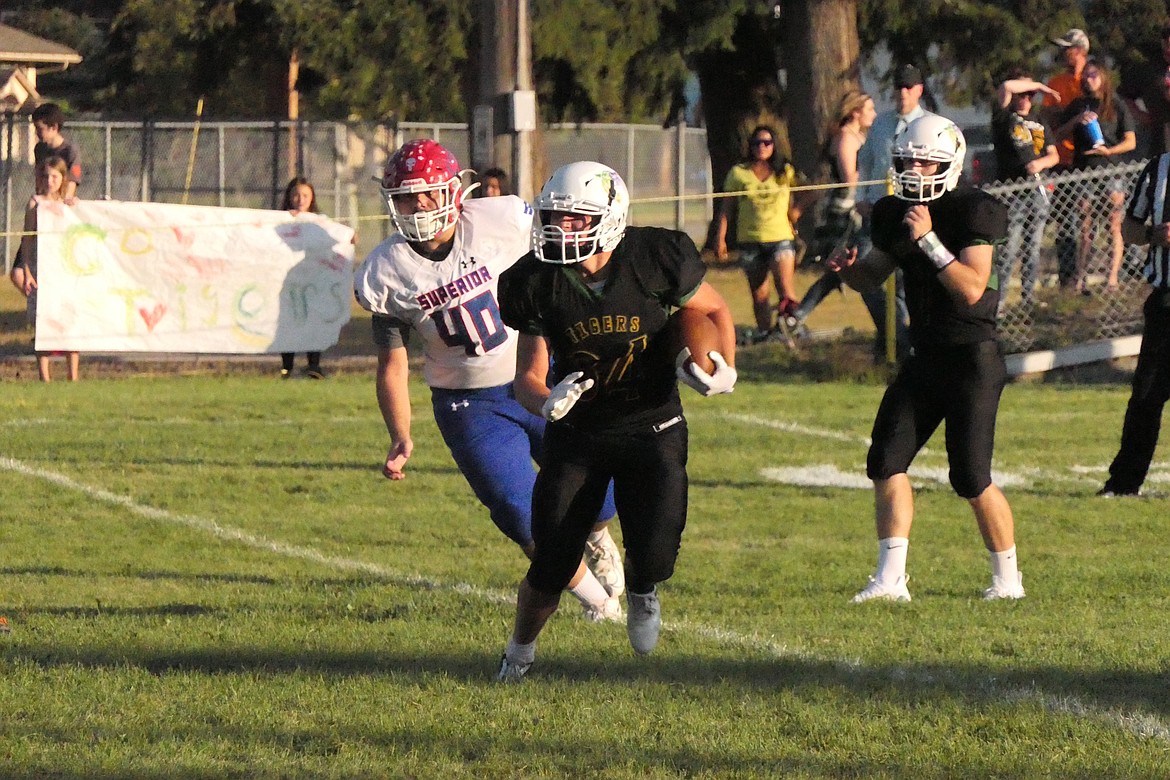 St. Regis running back John Pruitt (with ball) is chased by Superior defensive lineman Wyatt Haworth during the Bobcats win over I-90 rivalry action Friday night in St. Regis.  (Chuck Bandel/MI-VP)