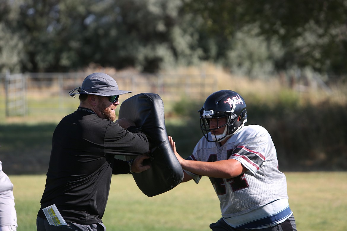 ACH head coach Brandon Walsh (left) works with the offensive line during practice.