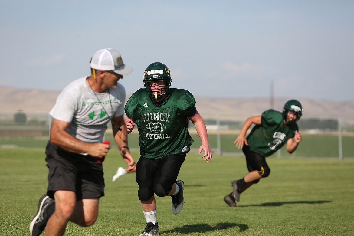 Defensive lineman Robert Bensch chases after head coach Russ Elliott during a team defense session.