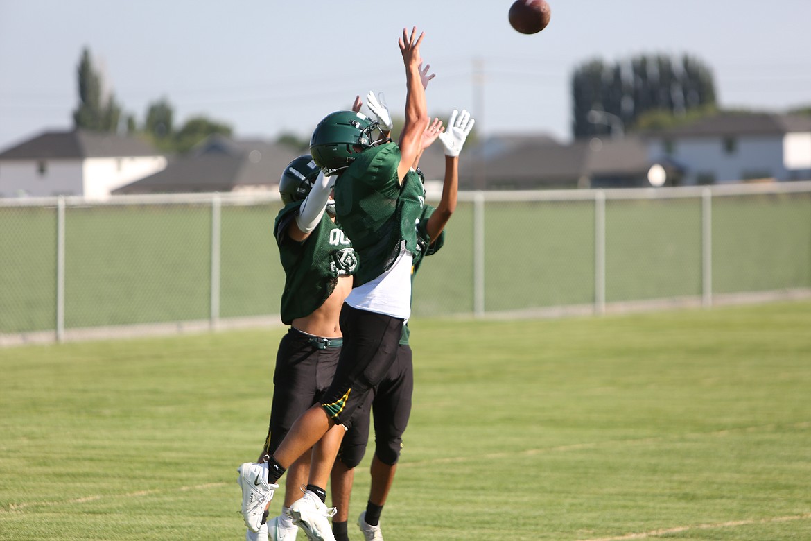 A trio of Quincy defenders leap up to break up a pass during practice.