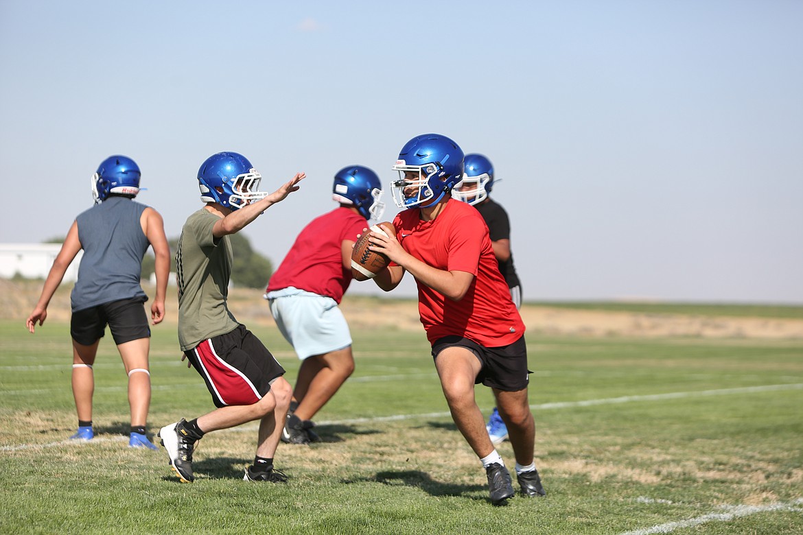 Quarterback Elijah Ruiz evades pressure during a walkthrough practice, before unloading a deep pass.