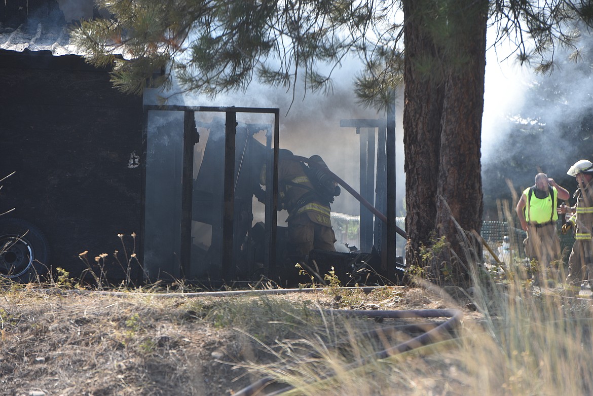 A Libby Volunteer Fire Department firefighter checks on a hot spot at a garage fire Wednesday afternoon at Echo Lane off of U.S 2 east of Libby. (Scott Shindledecker/The Western News)