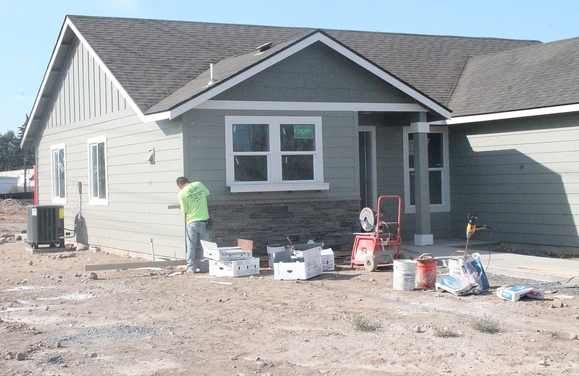 A worker adds masonry accents to a house in the Maple Grove development in Moses Lake. The first homes will be ready to move into later this month.