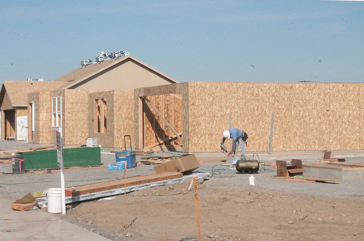 A construction worker works on a home in the Maple Grove development in Moses Lake. Homes are selling faster than they can be built, according to real estate agent Mark Fancher, who is handling sales for the development.