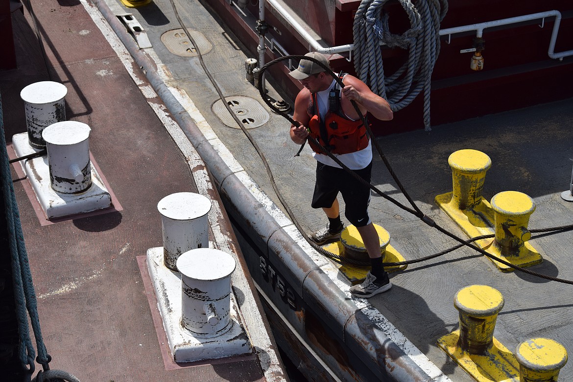 Deckhand Sean Malloy prepares to loop a 1.5-inch steel cable to lash barges together and hold them secure. Captain and pilot Troy Moore, who started out his career as a deckhand, said the work is physically demanding and very tough. “That cable can make a young man old,” he said.