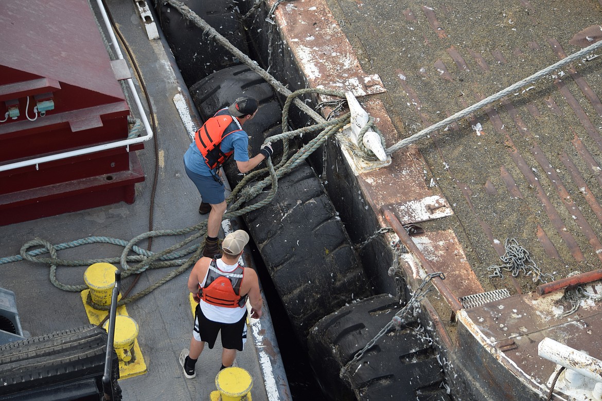 Deckhands Colby Glaze, top, and Sean Malloy lash their tow to a pier. Shipping professionals like Glaze and Malloy help to ensure grain and other products are shipped economically, which helps keep the prices of products made with their cargo affordable for consumers.