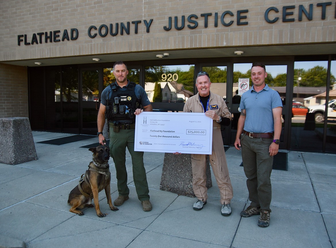 Randolph Mahoney, chairman of Hall-Halliburton Foundation, center, presents a donation to representatives of the Flathead K9 Foundation, Flathead County Sheriff’s Office K-9 handler and Deputy Sheriff Patrick McGauley and his K-9 Audie, and Alex Moore, treasurer for the foundation, Wednesday outside the Flathead County Justice Center. (Heidi Desch/Daily Inter Lake)