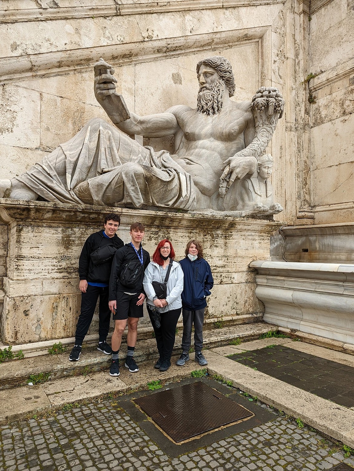 From left, Carter Woodman, Tristan Demoe, Lakes Middle School teacher Tanya Lilley and and Quinn Holt stand with a massive ancient statue while visiting Italy earlier this year.