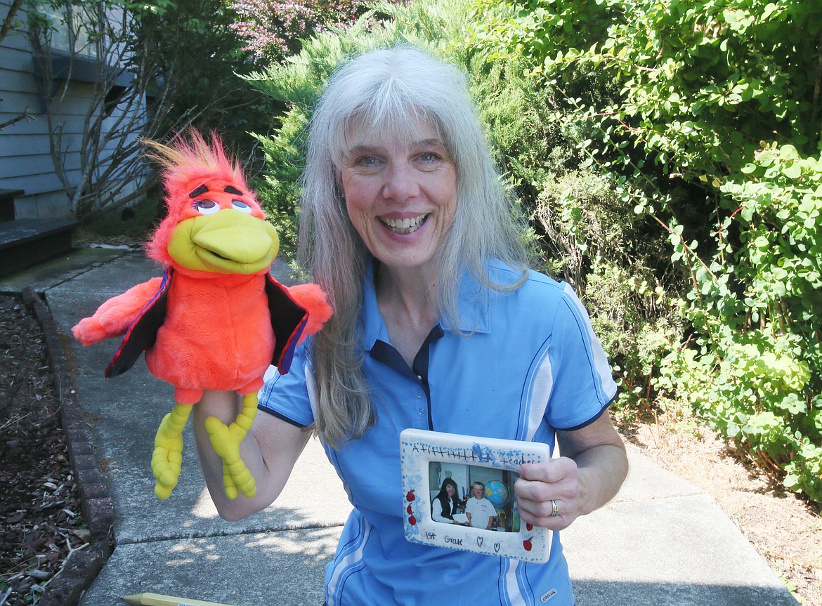 Dalton Elementary School first-grade teacher Nancy Nuttelman on Friday holds up classroom learning puppet Woody Woodpower and a photo from her 40 years of teaching in the Coeur d'Alene School District.