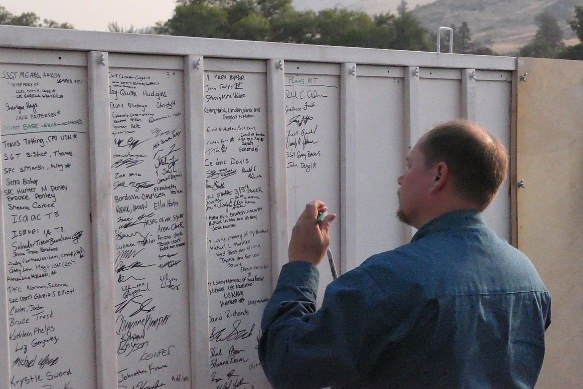 Army Veteran Jim Layton signs his name to the back of the traveling artwork that is crossing the country to bring awareness the the extent of Veteran suicides. Layton's friend recently took his own life. (Chuck Bandel/VP-MI)