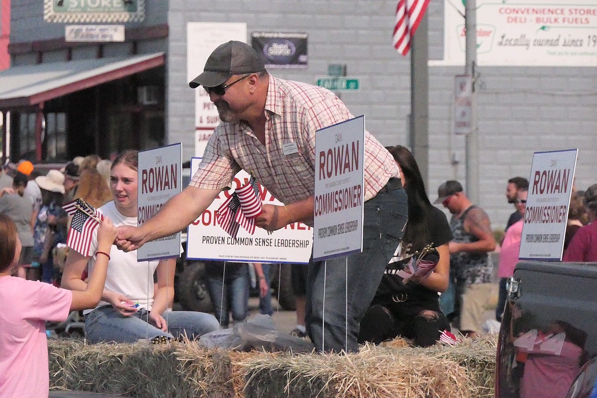 Plains Mayor and County Commissioner candidate Dan Rowan handing out American flags. (Chuck Bandel/Valley Press)