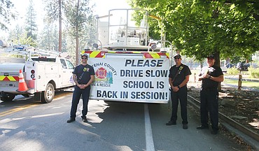 From left, Ryan Jaderquist, Sam LaPresta and Colter Smart of Kootenai County Fire and Rescue on Tuesday afternoon remind drivers near Ponderosa Elementary School in Post Falls to slow down now that school is back in session.