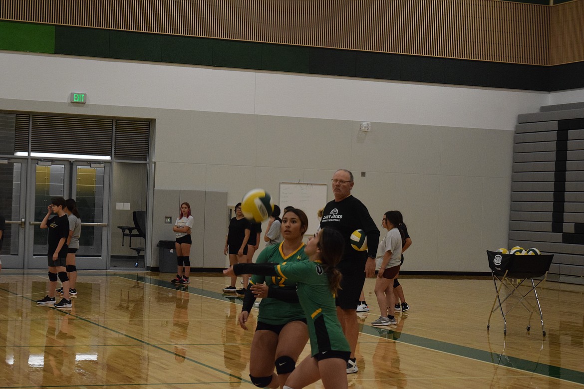 Quincy High School volleyball players return the ball under the watchful eye of Coach Dean Pratt during practice Friday.